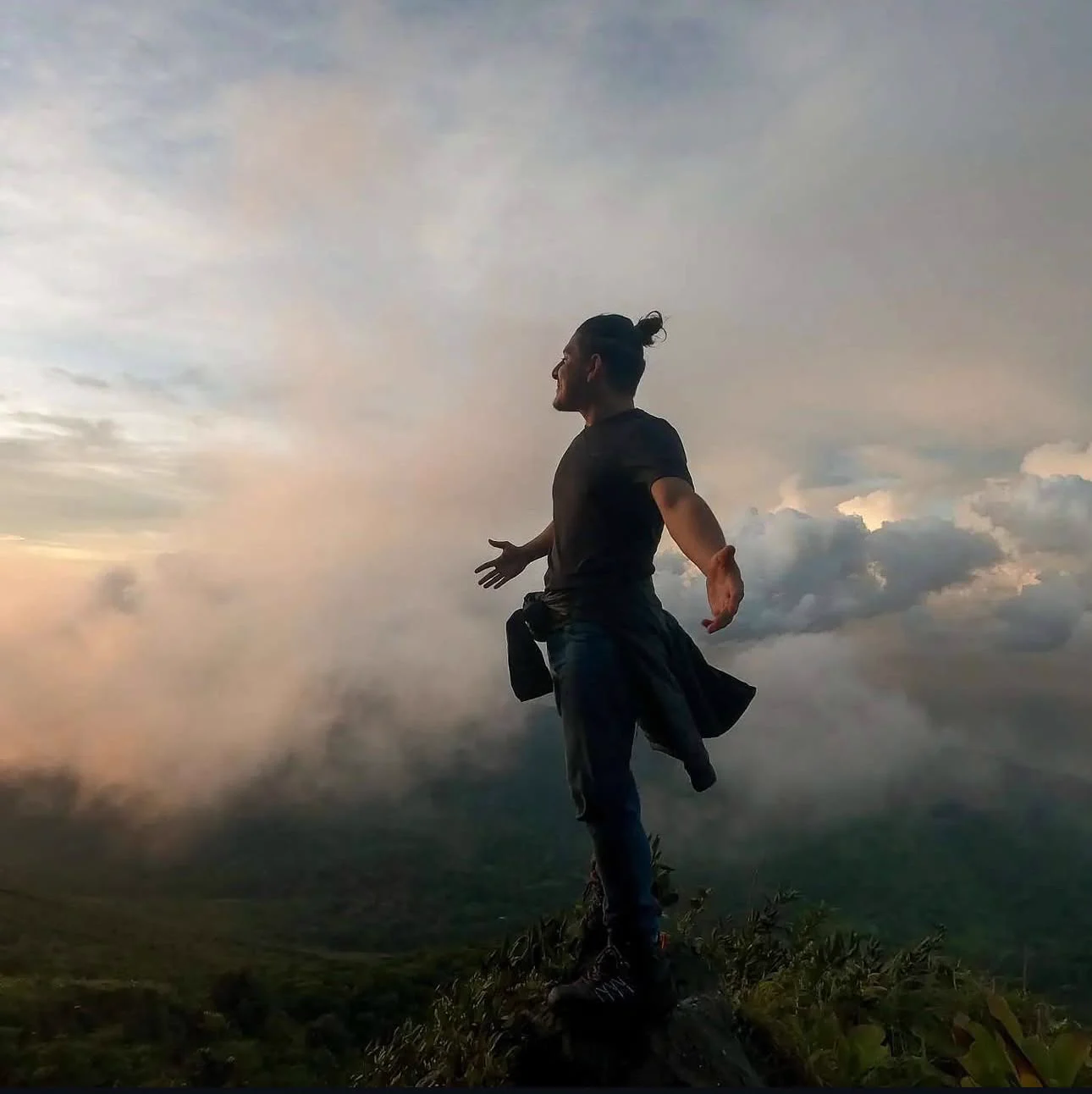 Benjamín Bautista con los brazos abiertos en la cima de una montaña al atardecer